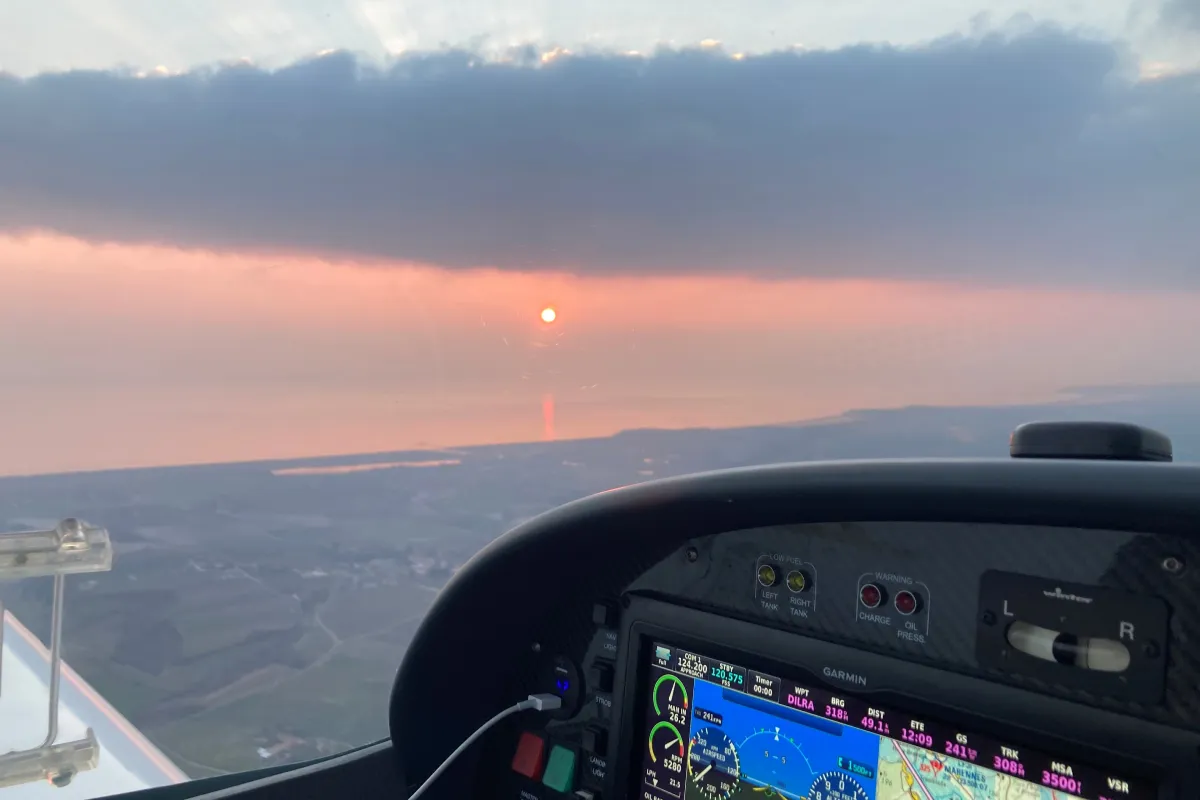 L'intérieur du cockpit de l'ULM VL3 en plein vol devant un coucher de soleil